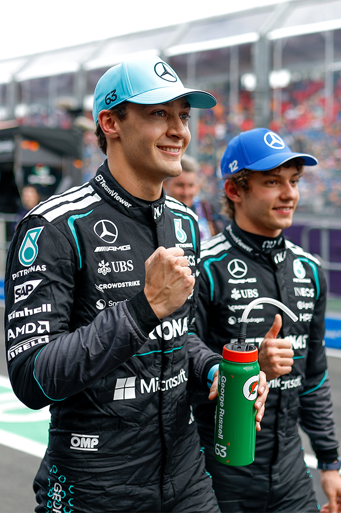 Two Formula 1 drivers with drink bottles at the racetrack.