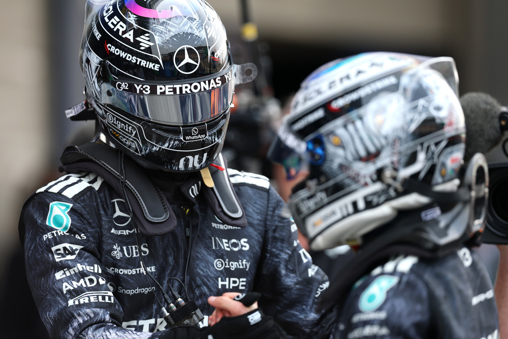Two Mercedes F1 drivers in racing suits and helmets